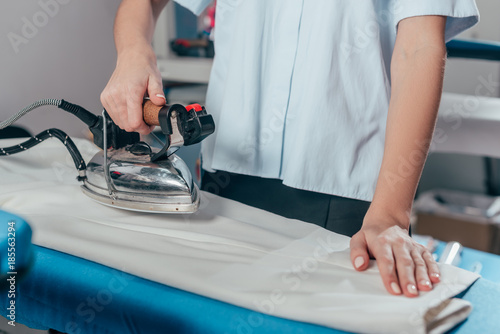 Fotografía cropped shot of female dry cleaning worker using industrial iron
