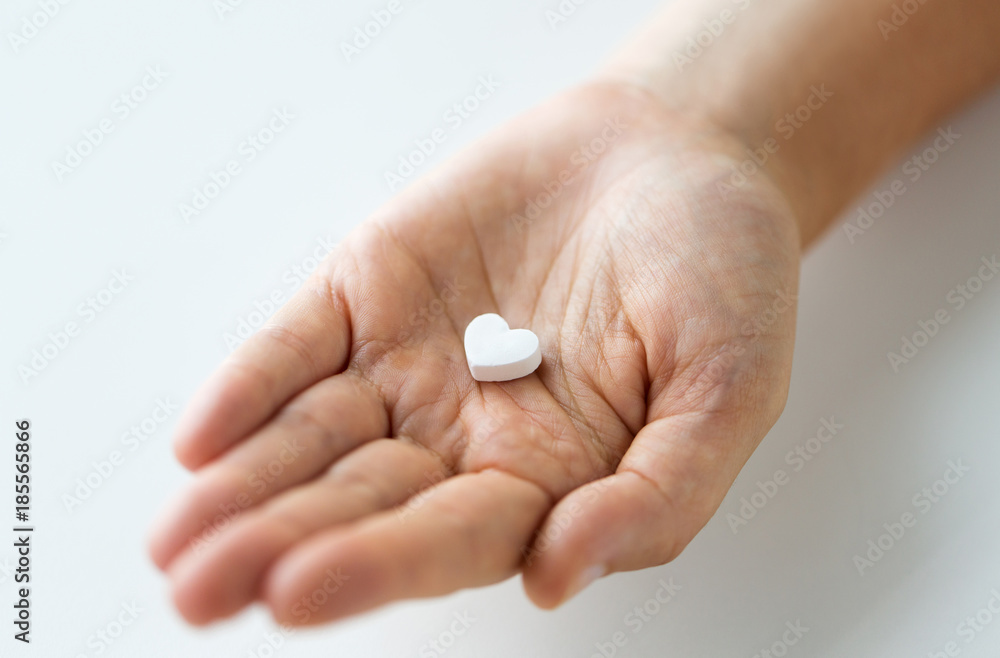 close up of hand holding medicine heart pill close up of hand holding medicine heart pill