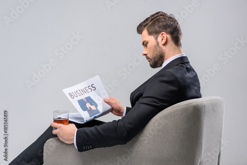 businessman reading newspaper and holding glass of whiskey