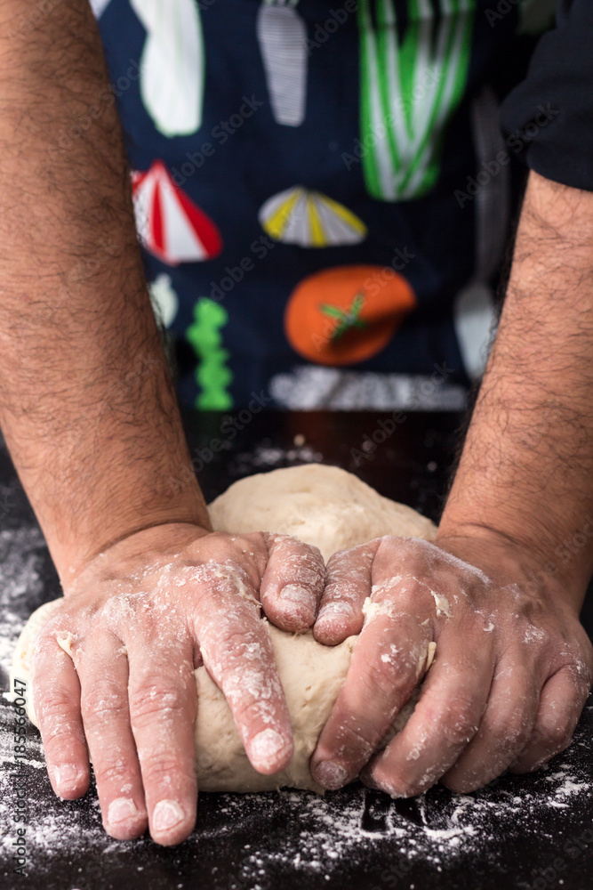 Male hands kneading dough, baking preparation closeup.
