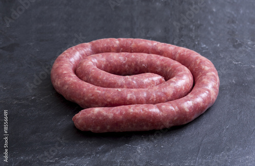 Rolled uncooked botifarra or Catalan sausage. Isolated over black slate photo