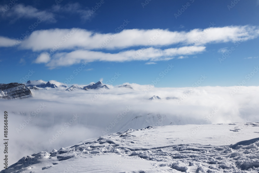 Snowy slope and sunlight mountains under clouds Snowy slope and sunlight mountains under clouds
