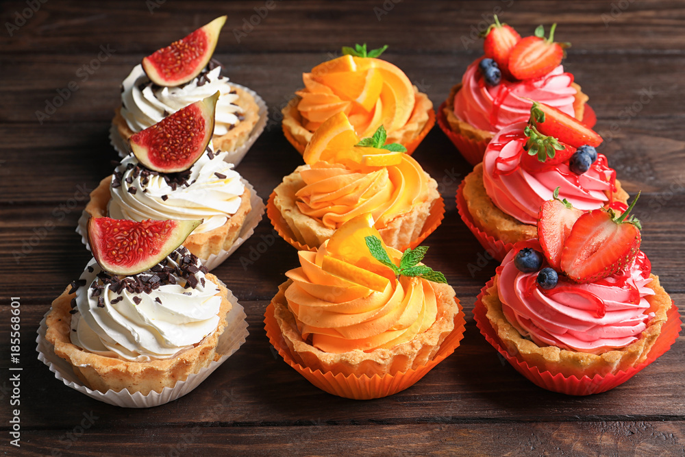 Tasty colorful cakes on wooden background