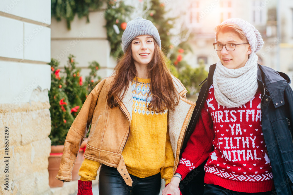 Christmas vacation holidays, love concept - trendy hipster couple iof lovers n warm knitted clothes walking in the street in winter time.