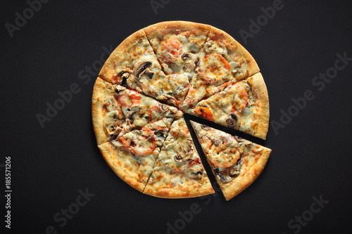 Fresh italian pizza with mushrooms, tomatoes, cheese, on black stone background