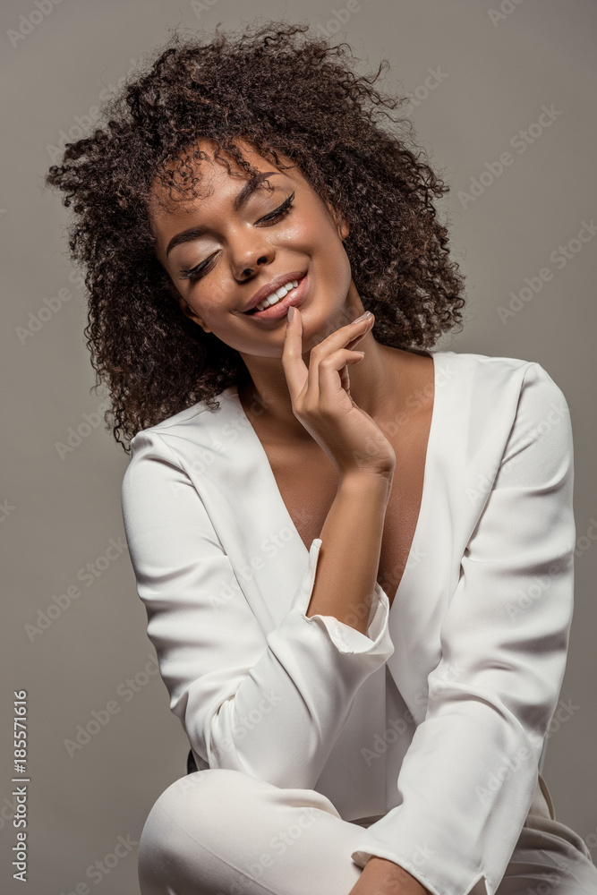 Young sensual african american woman in white shirt with finger on lips isolated on grey background Young sensual african american woman in white shirt with finger on lips isolated on grey background
