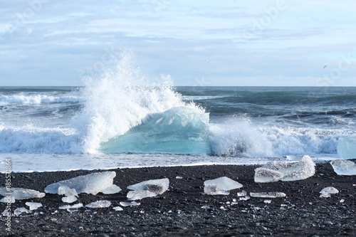 Ice berg with wave on a black beach in Iceland