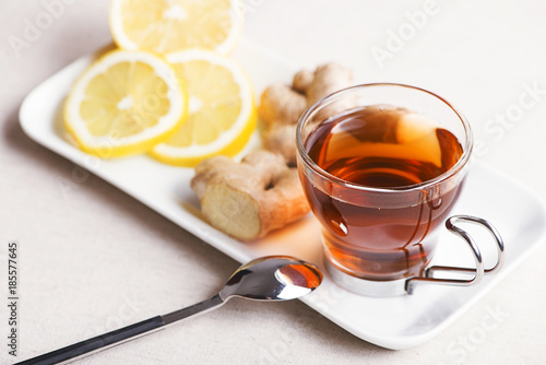 Tea cup with lemon and ginger on white plate. Infusion.