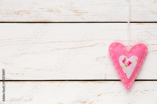 Valentine's Day concept with a pink felt handmade heart against white shabby wooden background, With pleanty of copy space for your text