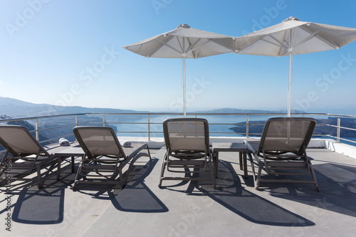 Sun loungers and parasol on the terrace overlooking the Mediterranean in Oia, Santorini