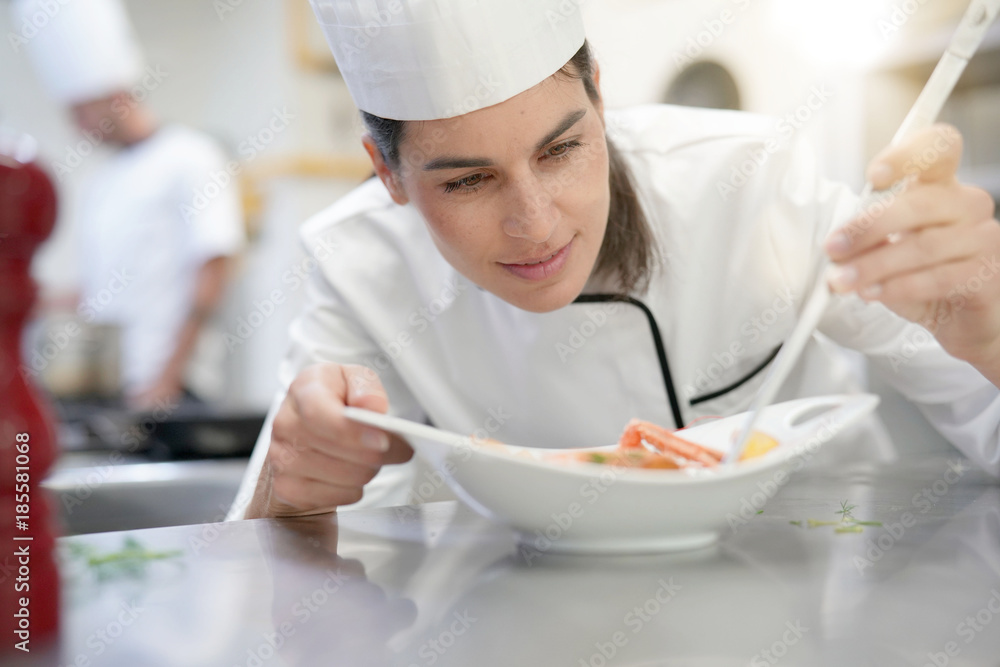 Professional cook garnishing plate in restaurant kitchen Professional cook garnishing plate in restaurant kitchen