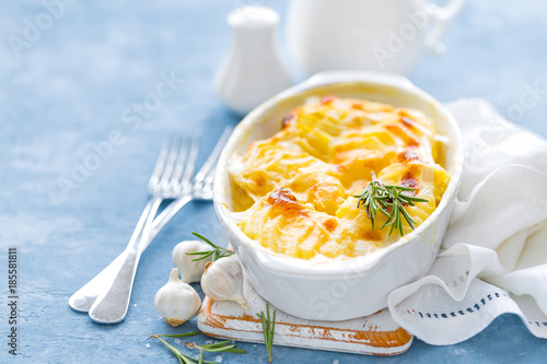 Baked potato gratin with garlic, cream and cheese, traditional french cuisine. White background photo
