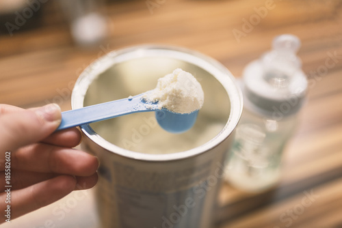 Powder milk for baby and blue spoon on light background close-up. Baby Milk Formula and Baby Bottles