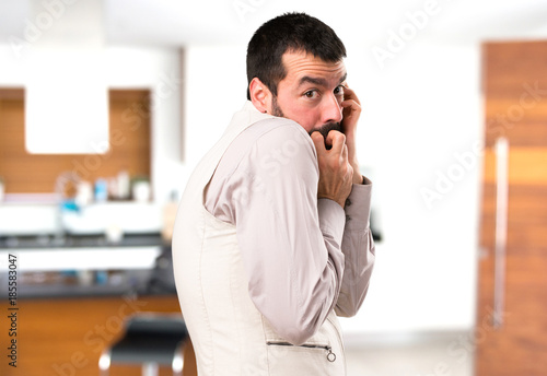 Frightened handsome man with vest inside house