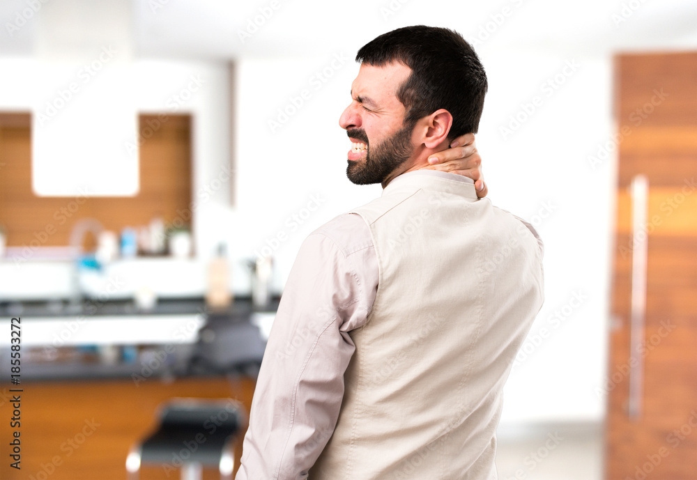 Fototapeta premium Handsome man with vest with neck pain inside house