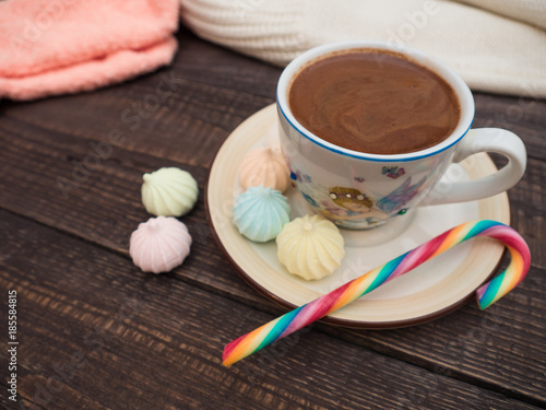 Cocoa with foam, sweet candy and colored bisse on a wooden table