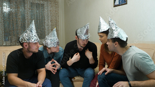 Friends in foil on the head of the house. Gathering of friends about listening to their ideas of extraterrestrial civilizations