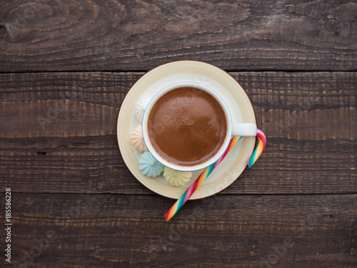 Cocoa with foam, sweet candy and colored bisse on a wooden table photo