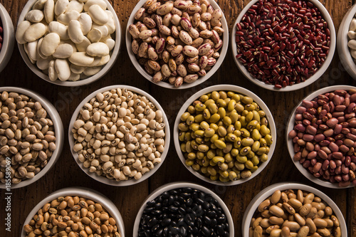 Assorted beans in bowls on wood background