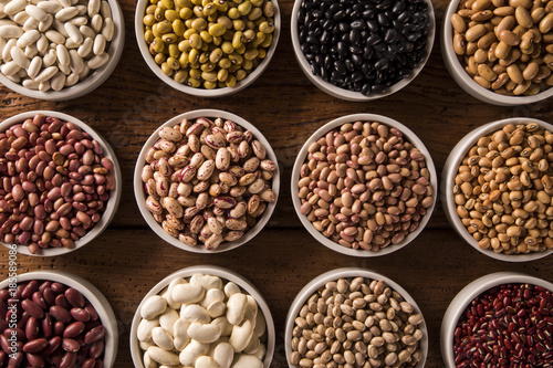 Assorted beans in bowls on wood background