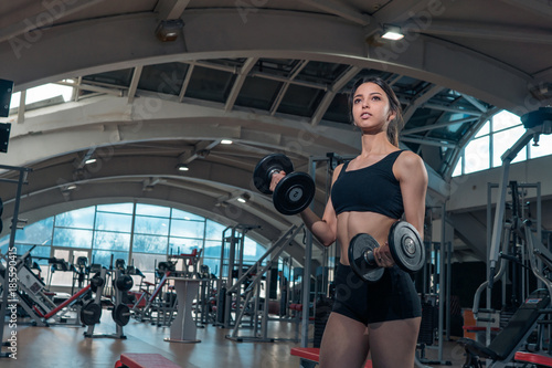 Girl model posing with weights at the gym