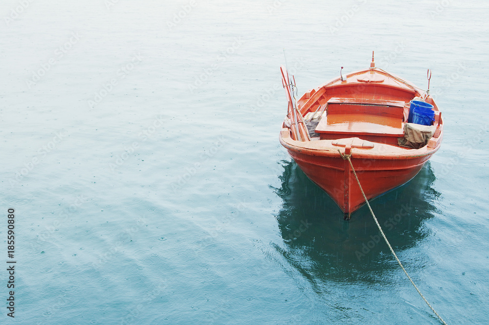 Obraz premium Red Mediterranean fishing boat in the sea in summer cloudy day. Lonely red boat