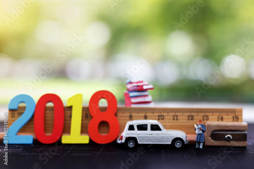 Miniatures people reading with car, ruler book and number 2018. education or business concept..