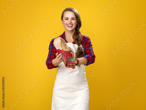 woman cook isolated on yellow background showing fresh bread