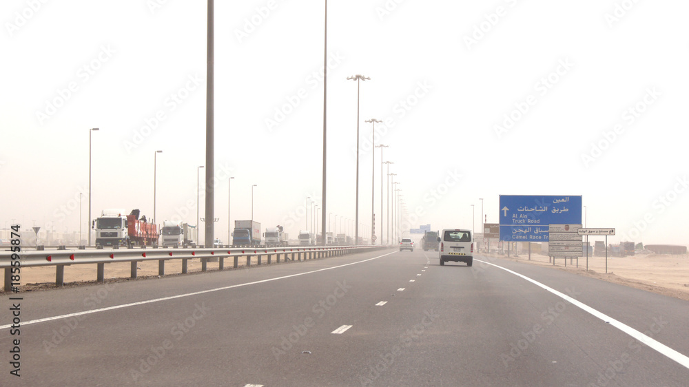ABU DHABI, UNITED ARAB EMIRATES - APRIL 3rd, 2014: Trucks driving on a desert motorway in the United Arab Emirates with heat haze