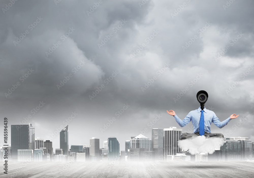 Camera headed man sitting in lotus pose on cloud against modern cityscape Camera headed man sitting in lotus pose on cloud against modern cityscape