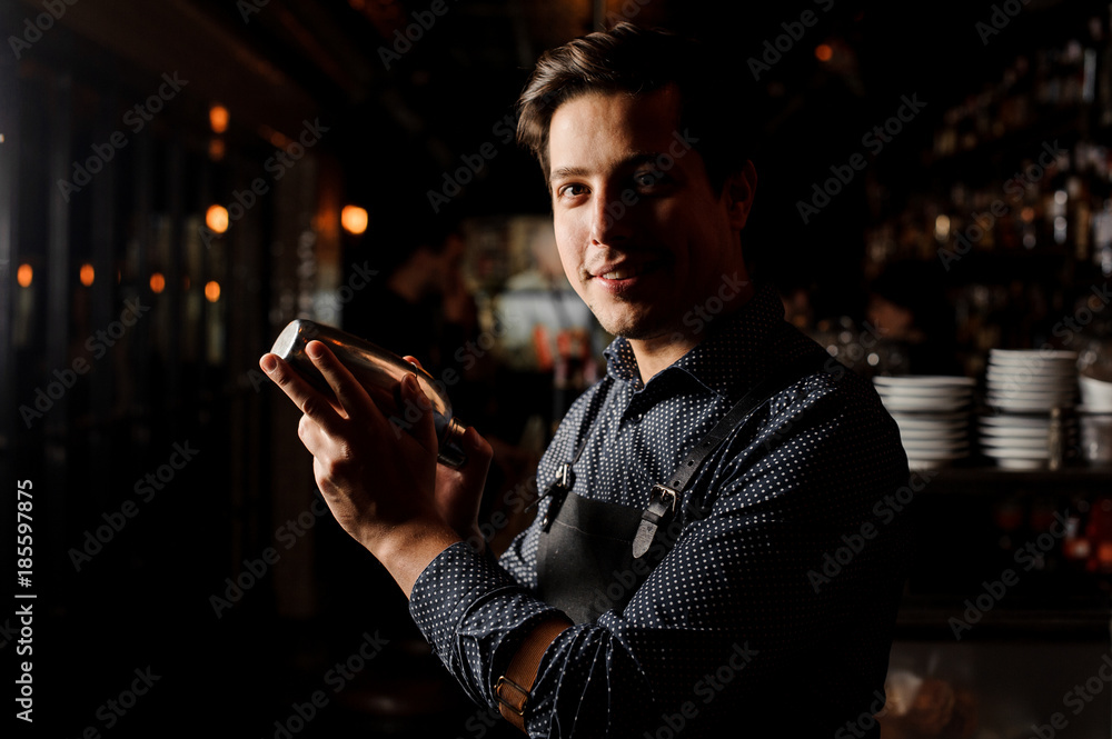 Handsome bartender holding a shaker in hand Handsome bartender holding a shaker in hand