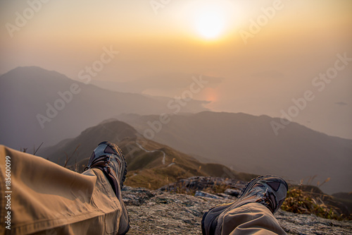 shoes and leg of hiker sit with fog at sunrise in winter, Lantau Peak, Hong Kong