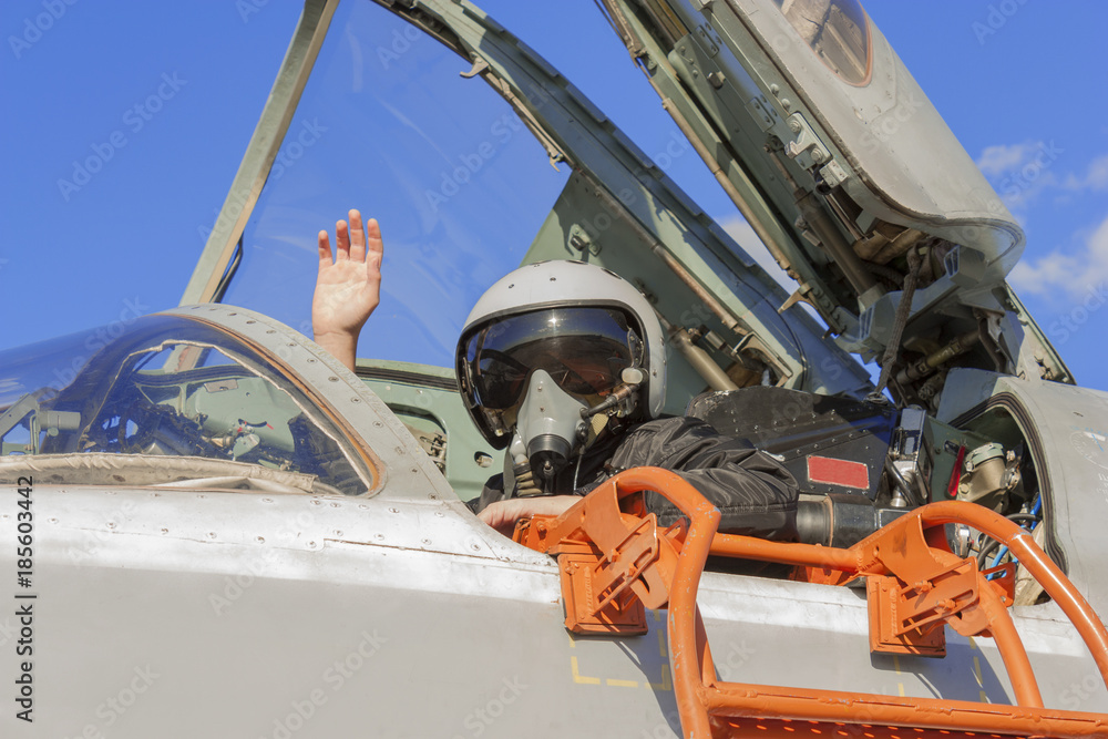 Military pilot in cockpit jet plane with a raised hand
