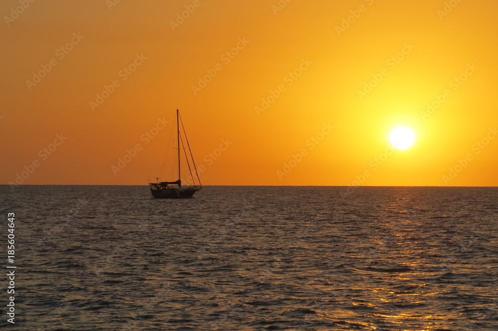 sail boat sunset on ocean red orange sinking sun in sea