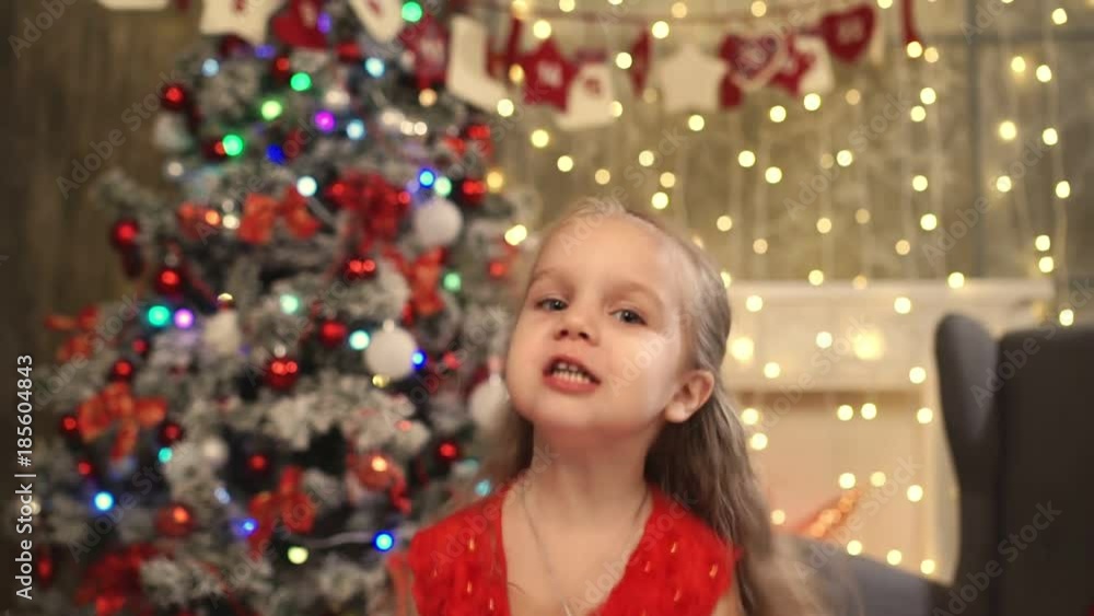 Happy little girl in red dress jump with gift box in hands in the New Year's interior Happy little girl in red dress jump with gift box in hands in the New Year's interior