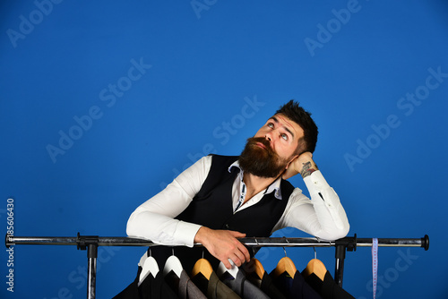 Businessman in vest near row of suits in shop. photo