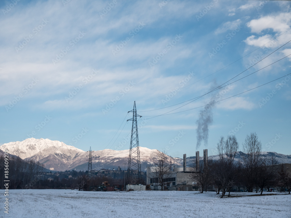 Biella, Italia - December 15, 2017: Industrial scenery covered by snow at the foot of the Alps, factory with chimneys that smoke, in the country of Biella international manufacturer of precious wool