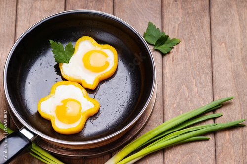 Bell pepper egg rings on a cooking pan, parsley and green onion 