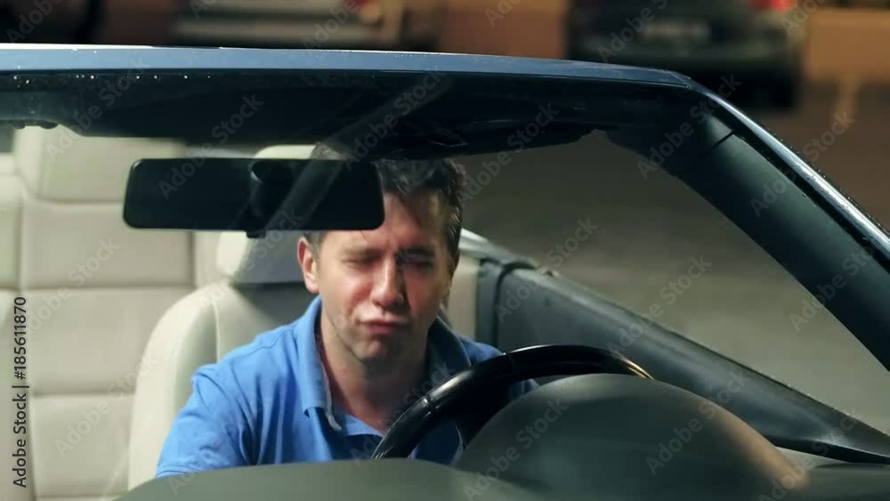 Handsome man sitting in cabriolet singing song and showing rock and roll sign Handsome man sitting in cabriolet singing song and showing rock and roll sign