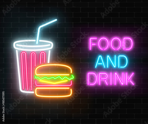 Neon food and drink glowing signboard on a dark brick wall background. Burger and plastic cup of beverage signs.