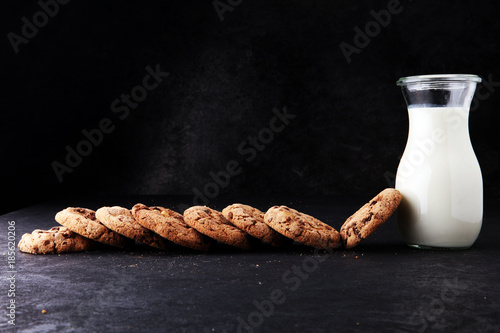 Chocolate chip cookies with milk on dark grey table photo