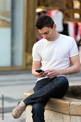 Portrait of a trendy young man touching mobile screen