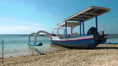 Indonesian Jakung outrigger canoe boat tied to the beach on Gili Meno Pacific island beach on July 3, 2017 in Indonesia photo