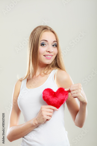 Smiling woman holding red heart love symbol
