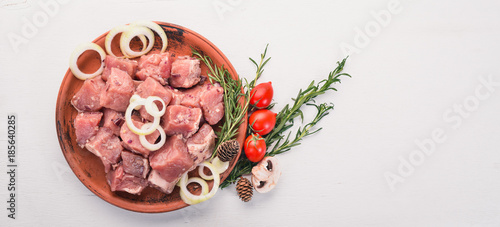 Raw meat is cooked for shish kebab on a wooden background. On the plate Top view. Free space for text.