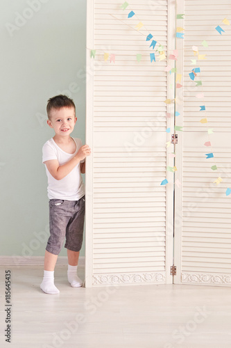 happy kid behind door. the boy plays. He hides behind the white door