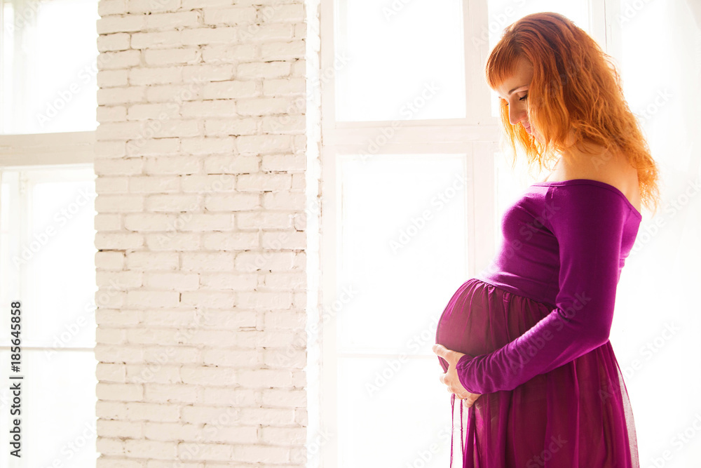 pregnant woman in purple dress in white room