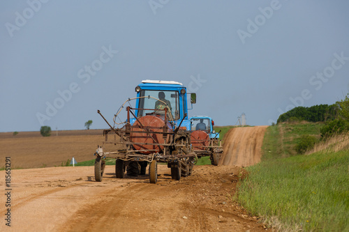 Agricultural fields in summer. The sown fields are wheat. Combine and tractor harvest.