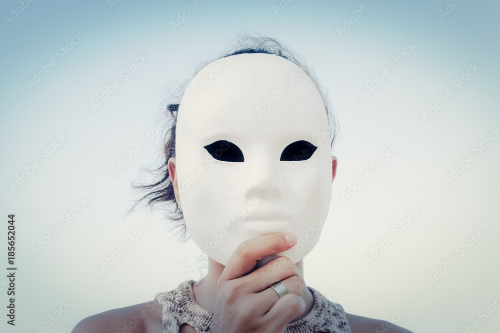 A mysterious woman wearing a lifeless white mask. Close-up symbolic shot.  Outdoors, blue sky. Secrets, mystery, unknown. Stock Photo | Adobe Stock