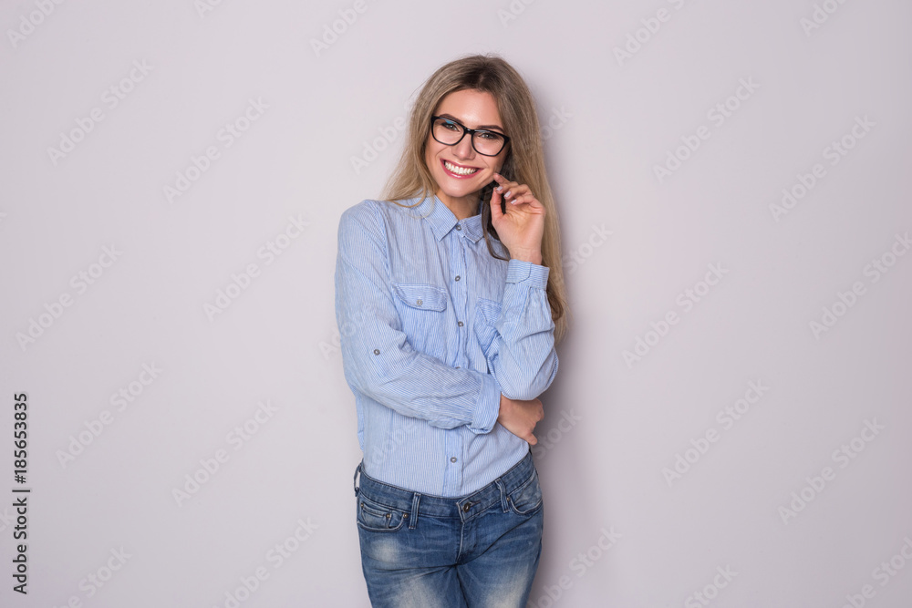 Happy blonde business woman in eyeglasses looking at the camera over gray background. Happy blonde business woman in eyeglasses looking at the camera over gray background.